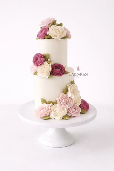 Elegant two-tier white cake adorned with realistic pink and white buttercream flowers.