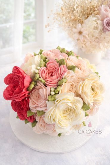 Beautiful cake decorated with intricate buttercream flowers in shades of red, pink, and cream.