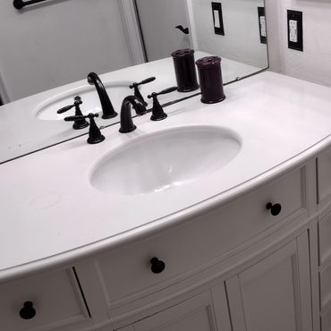 Modern white bathroom vanity with black fixtures and patterned floor tiles.