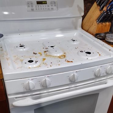 A dirty white stove with missing burners and food stains.
