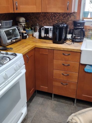Cozy kitchen corner with wooden cabinets, appliances, and a curious pug on the floor.
