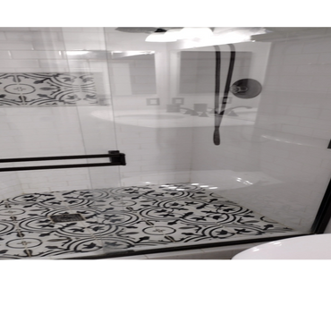 Shower with intricate black and white patterned tiles and glass door.