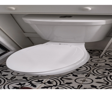 A white toilet with a closed lid on patterned black-and-white floor tiles.