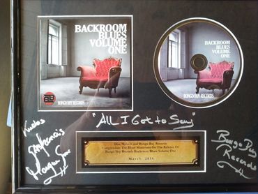 Framed album display for "Backroom Blues Volume One" with signatures and a congratulatory plaque.
