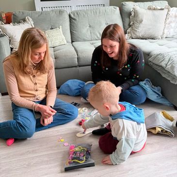Two women and a child playing on the floor.