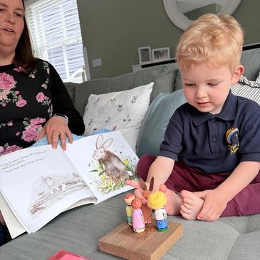 Child playing with toy figurines and an adult reading a book.