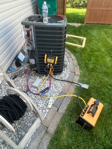 Outdoor air conditioning unit undergoing maintenance with tools and equipment.