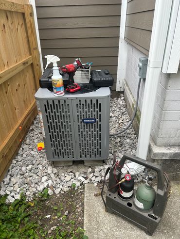 Outdoor HVAC unit with tools and refrigerant tanks.