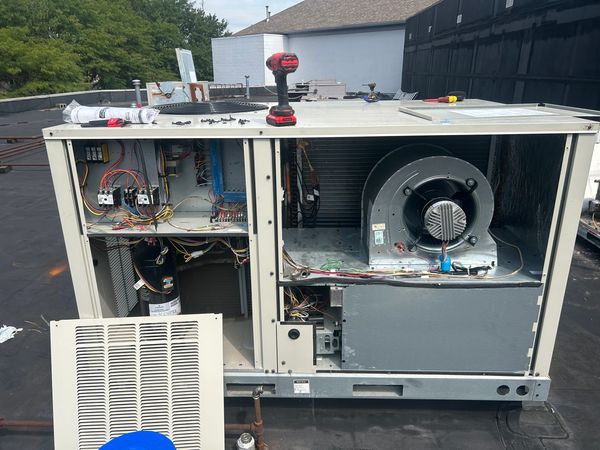 Open HVAC unit with tools on top during repair.