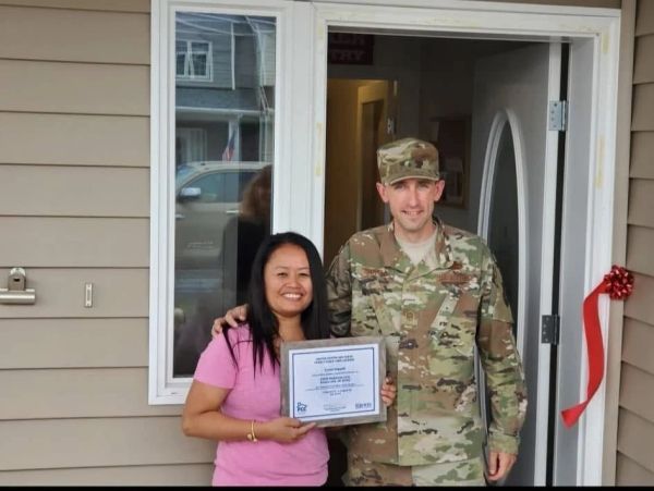 Woman with certificate and soldier standing at doorway.