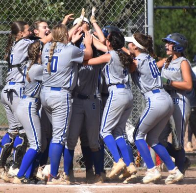 A group of softball players celebrating on the field.
