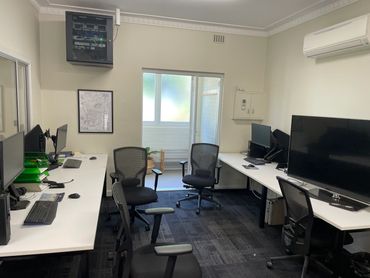 Modern office with multiple desks, monitors, and ergonomic chairs.