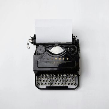 Vintage black typewriter with blank paper on white background.