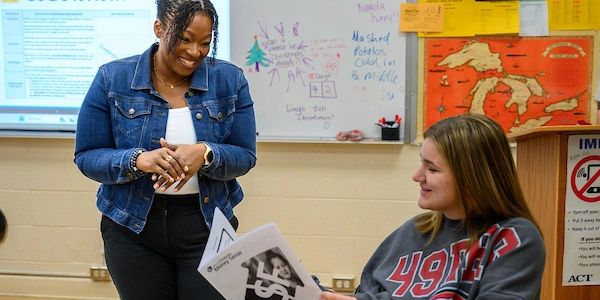 Teacher engaging with student in classroom.