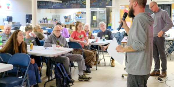A man speaks to an attentive audience in a casual meeting.