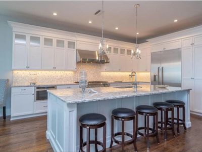 White kitchen with light gray and white speckled granite countertops and a full backsplash. 