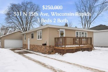 Single-story home with a wooden deck and attached garage in snowy Wisconsin Rapids.