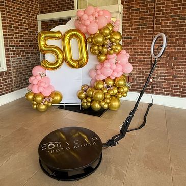 Photo booth setup with gold and pink balloons celebrating a 50th event.