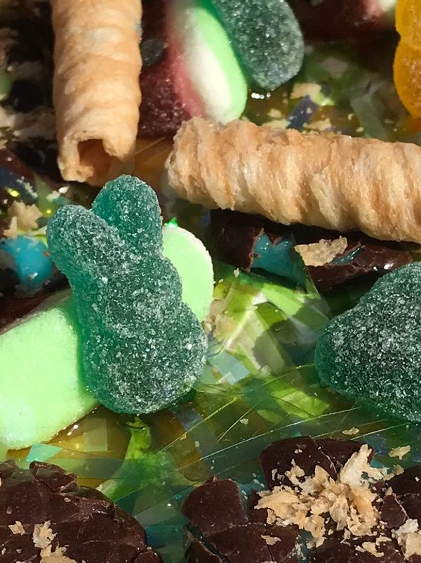 Close-up of assorted colorful candies and wafer rolls on a shiny surface.