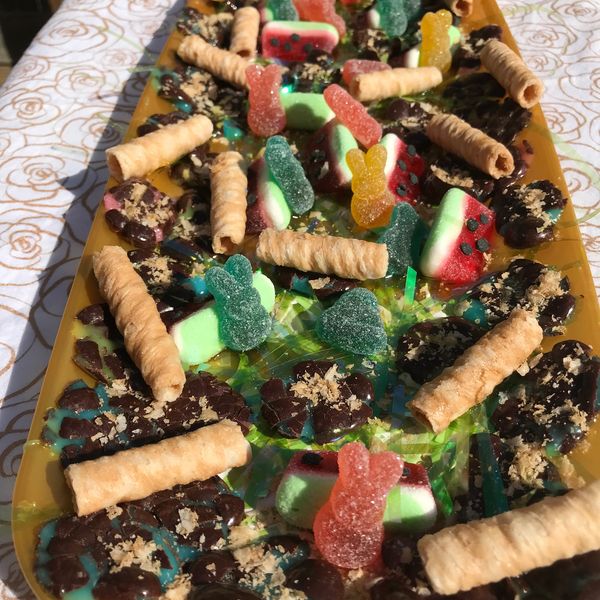 A colorful assortment of candies and wafer rolls on a yellow tray.