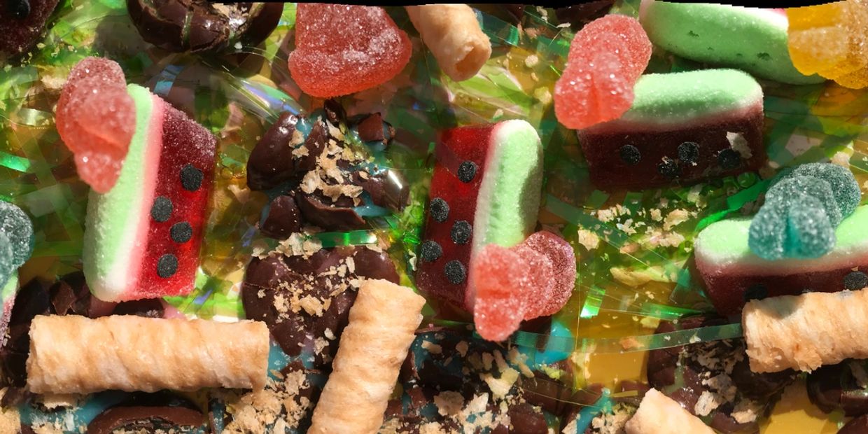 Colorful gummy candies and chocolate pieces on a shiny surface.