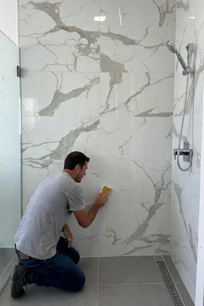 Man scrubbing marble bathroom tiles.
