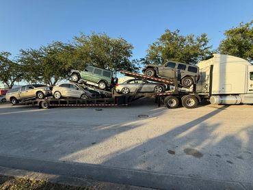 A car carrier truck loaded with multiple vehicles parked on the side of the road.