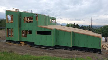 A modern house under construction with green ZIP System sheathing panels.