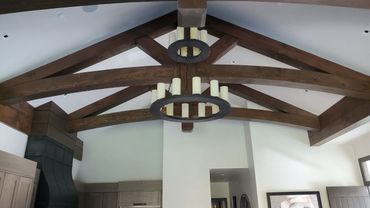Rustic wooden ceiling beams with a large chandelier in a modern room.