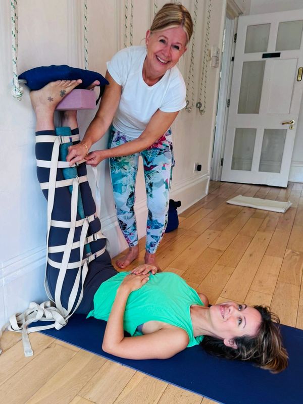 Woman receiving assisted leg stretch yoga pose.