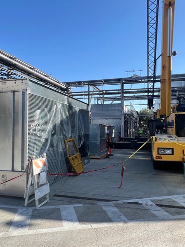 Yellow Link-Belt crane at an industrial site with metal structures and pipes.