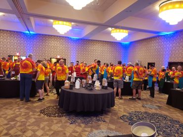 Group of people in tie-dye shirts at an indoor event with food tables.