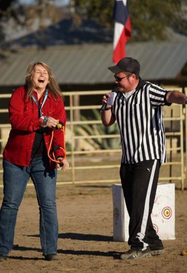 Two people laughing and enjoying an outdoor game with a Texas flag in the background.