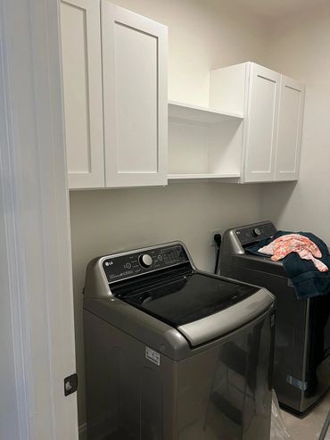 Modern laundry room with LG washer and dryer and white cabinets.