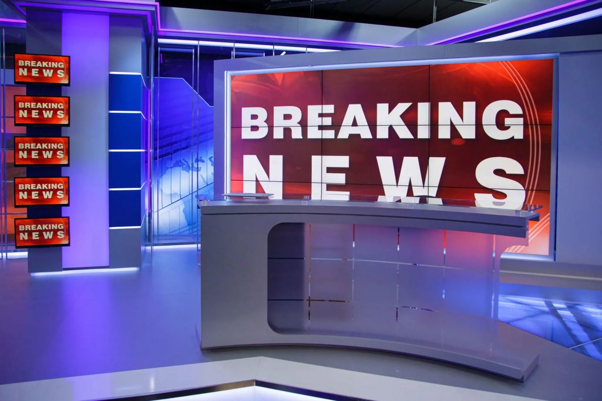Modern news studio with multiple 'Breaking News' screens and a sleek anchor desk.