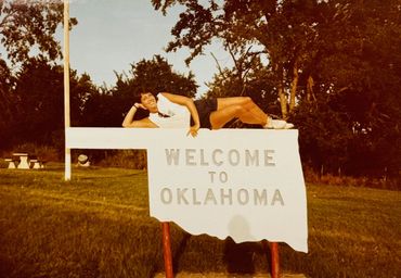 Picture of girl laying on sign of Welcome to Oklahoma