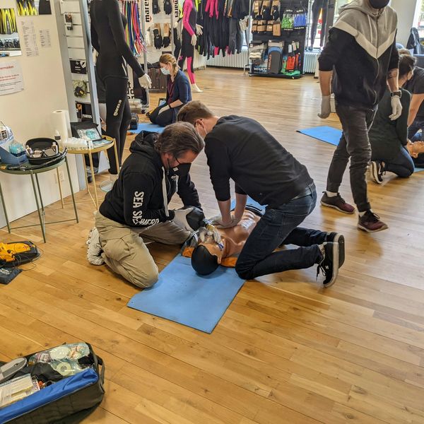 Students practicing chest compressions and AED placement on a manikin during on-site CPR training.