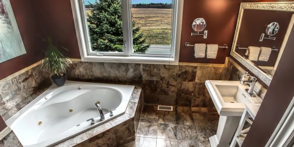 Cozy bathroom with a corner bathtub and large window overlooking a scenic view.
