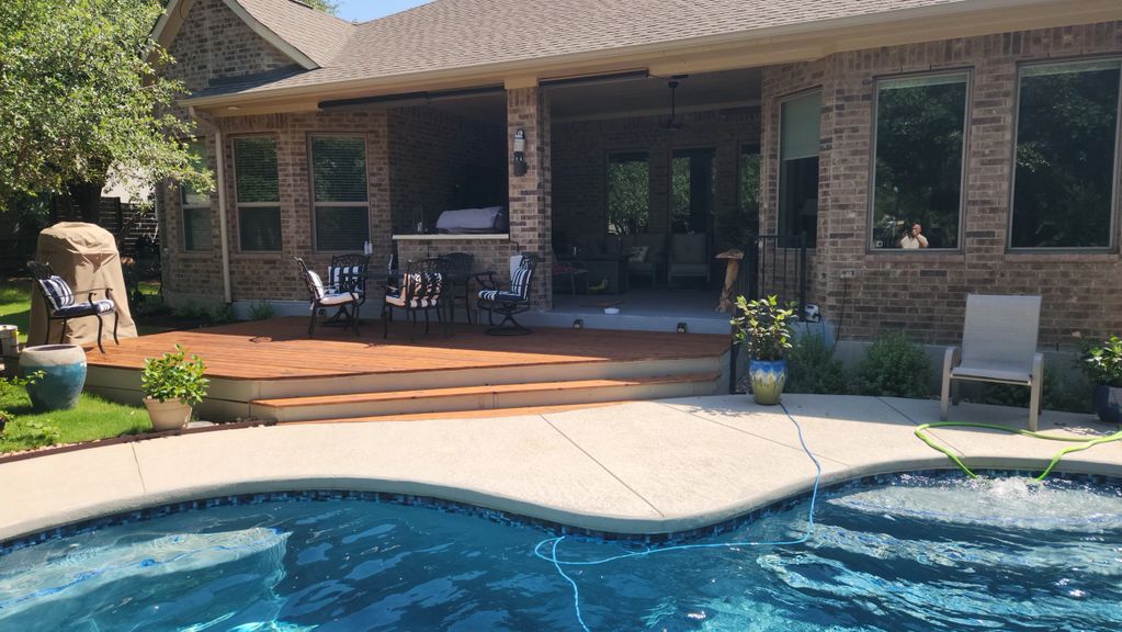 Backyard pool with patio seating and a covered porch on a sunny day.