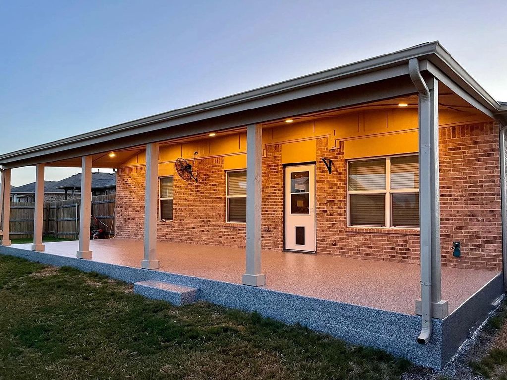 A spacious covered patio with brick walls and warm lighting at dusk.