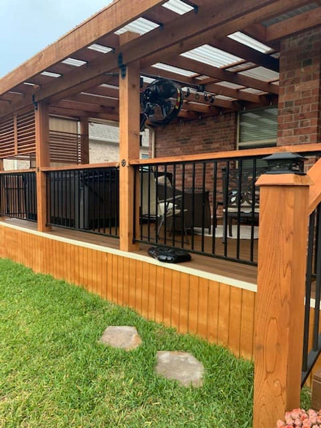 Wooden patio with black metal railing and green lawn.
