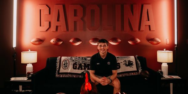 Young man sitting on a couch in a Carolina-themed room with football decor.