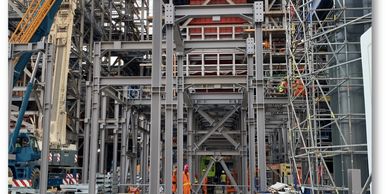 Construction site with workers and steel framework under assembly.