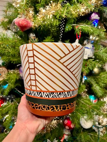 Hand painted terracotta pot with white and gold geometric lines and animal print accents.
