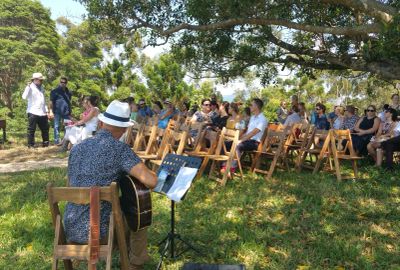 A man playing guitar outdoors for an audience.