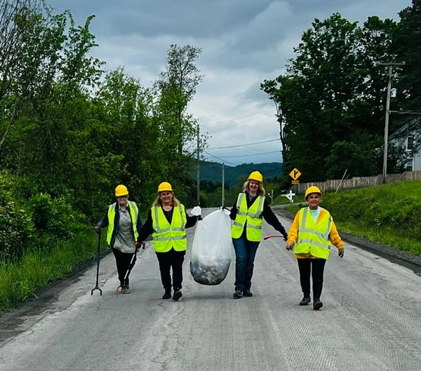four women in reflective vests walking in line during a cleanup