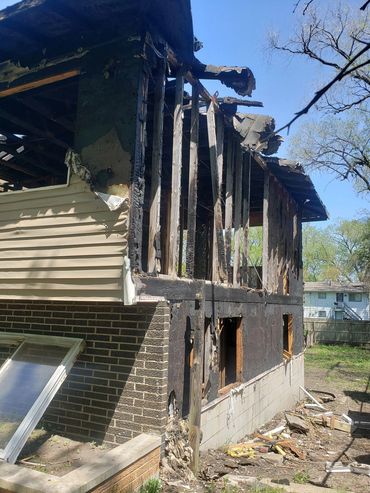 Partially burned house with significant fire damage and exposed wooden beams.