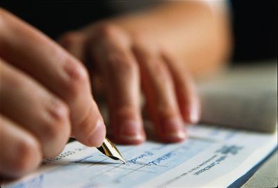 Image of a person's hands writing a check.  This photo has no link associated with it.  It is for ae