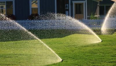 Photo of sprinklers watering grass in front of a house.  This photo no links.  It is for aesthetic p