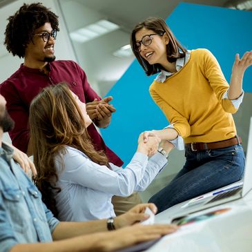 A handshake and a round of applause for a small team in an office
